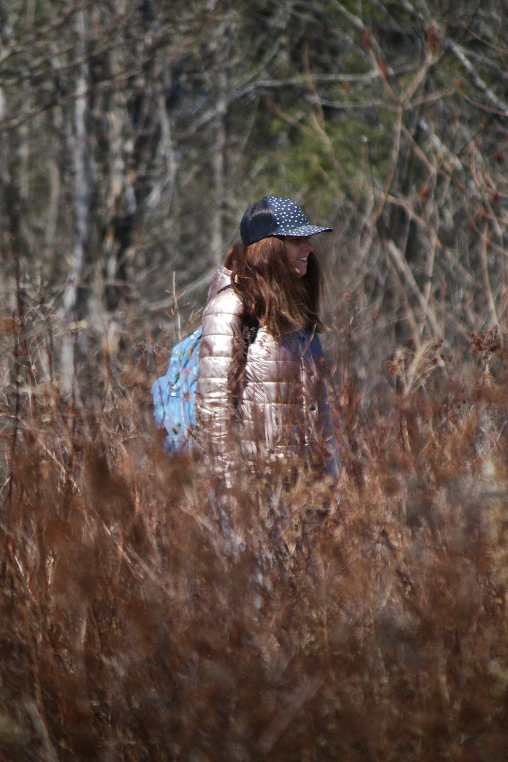 a woman walking through a field of tall grass