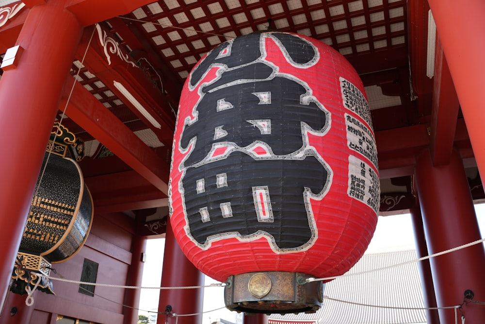 a red and black lantern hanging from a red pole
