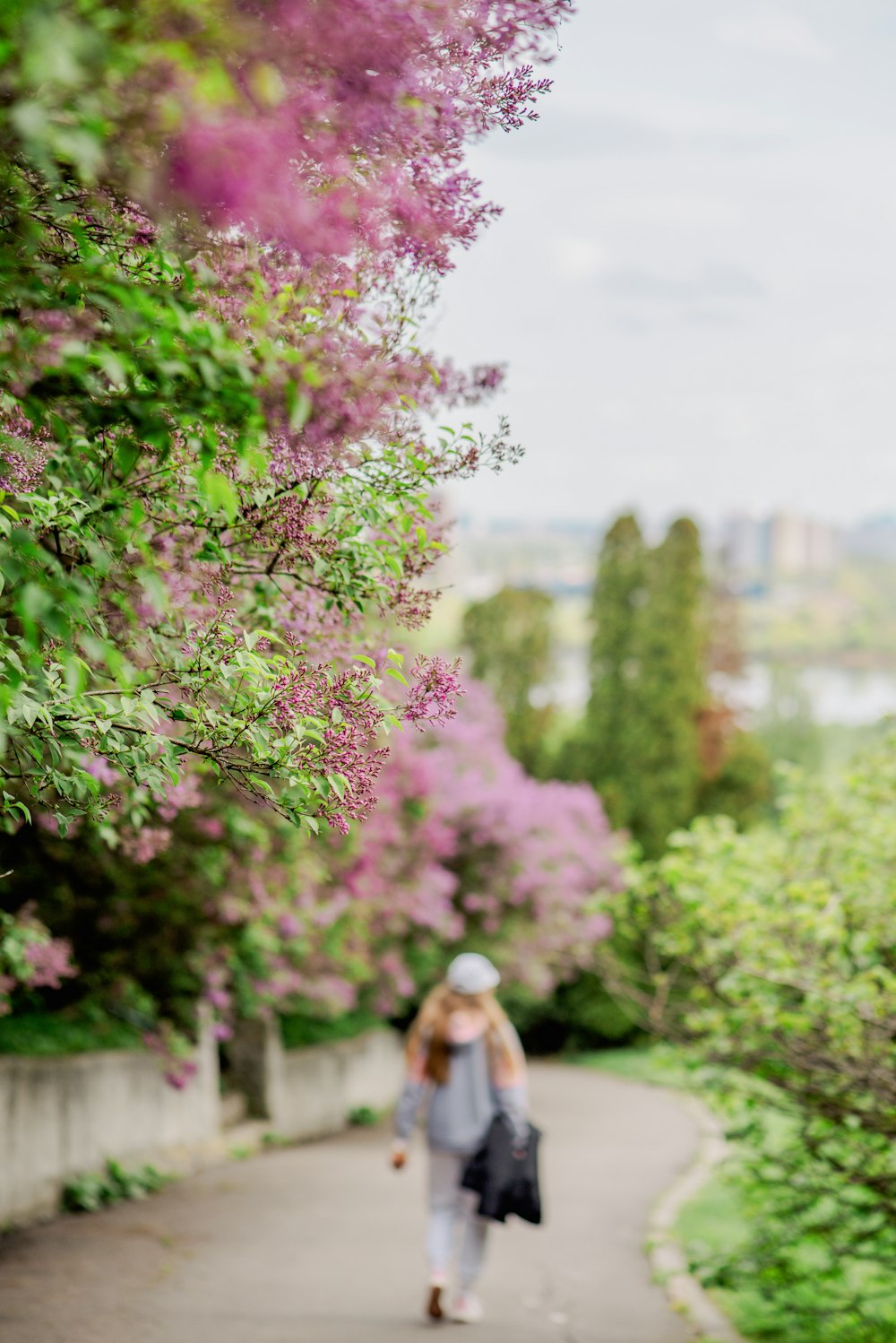 a woman is walking down a path in the park