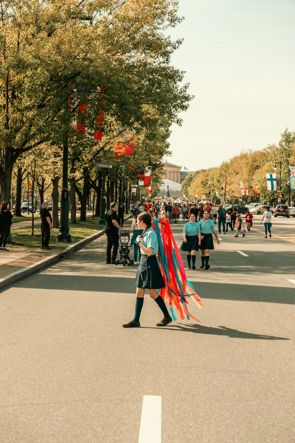 a woman walking down a street holding a kite