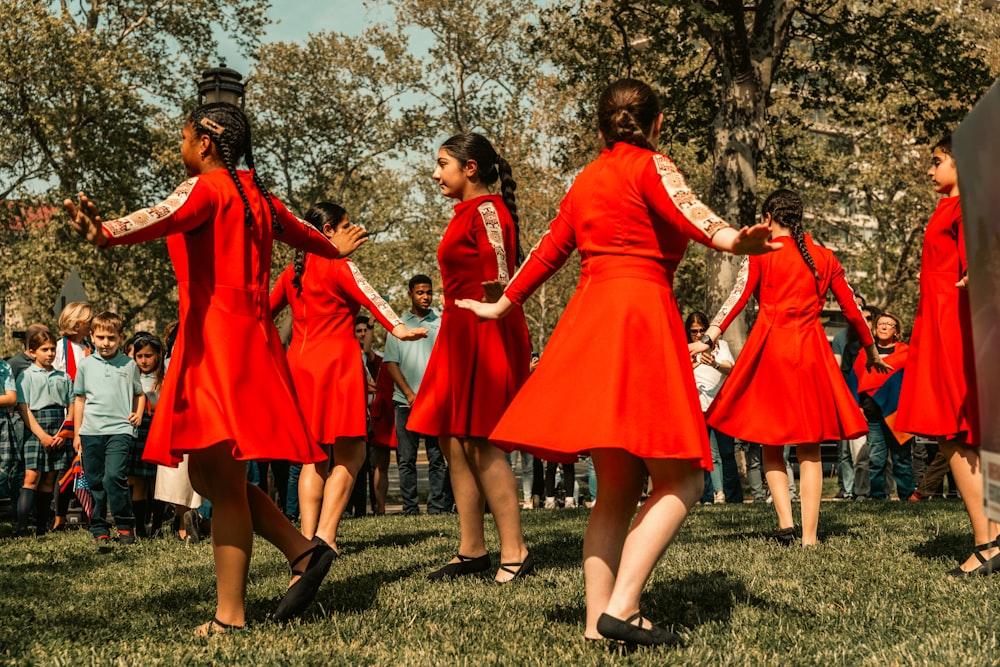 a group of women in red dresses dancing in a field