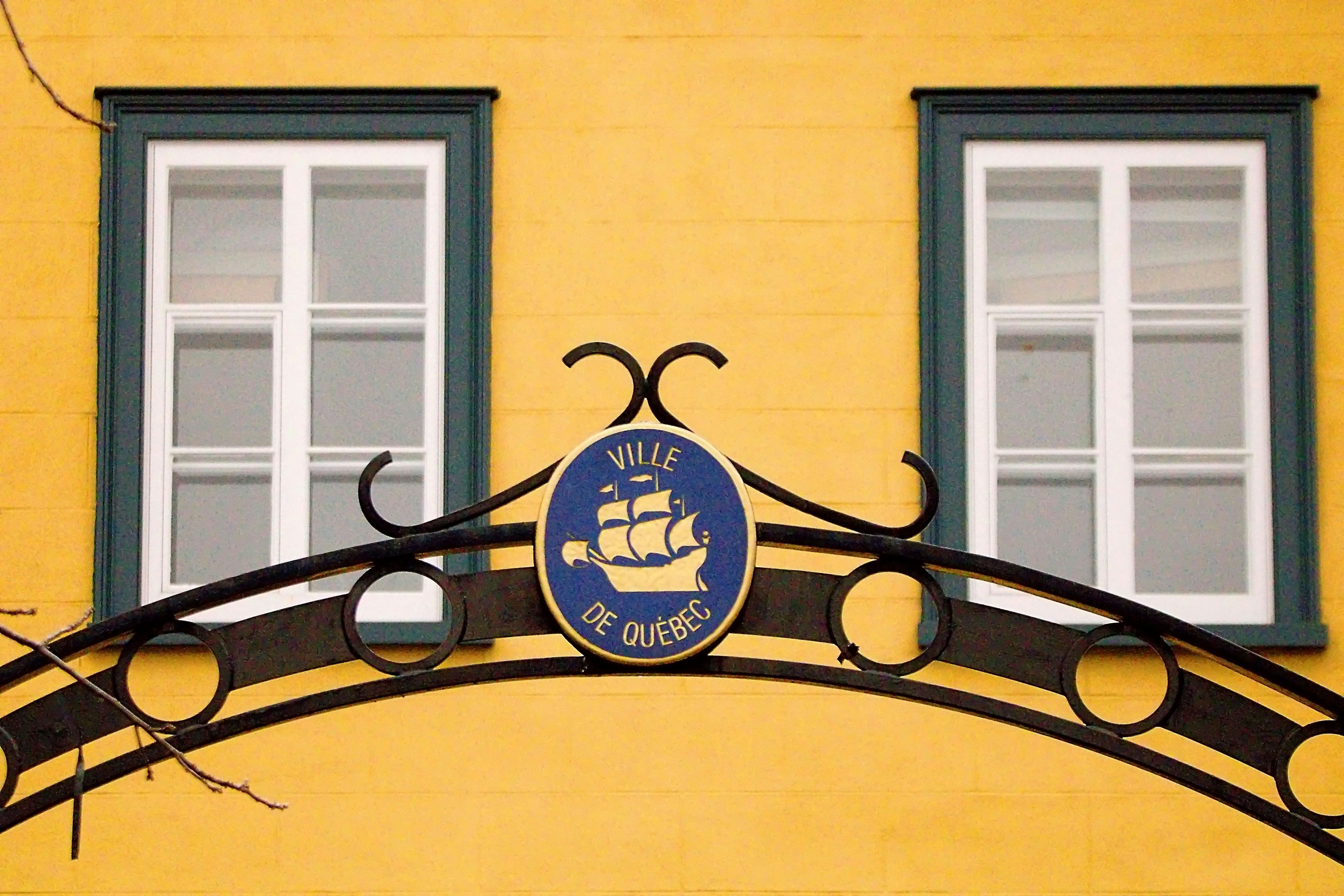 a yellow building with two windows and a sign on it