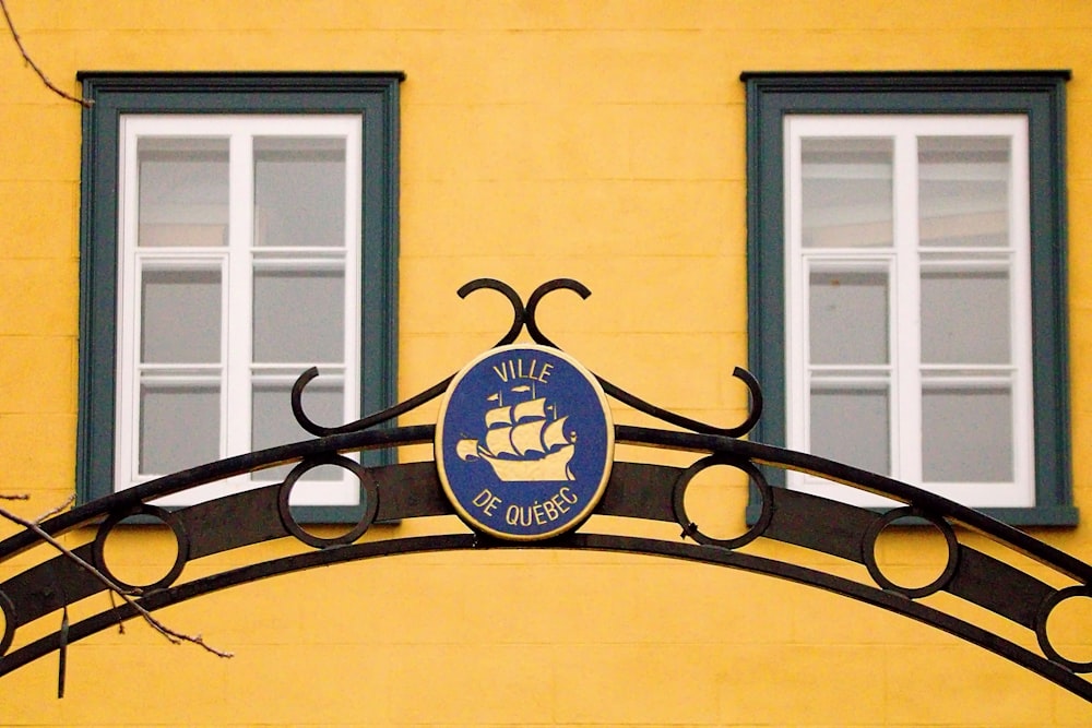 a yellow building with two windows and a sign on it