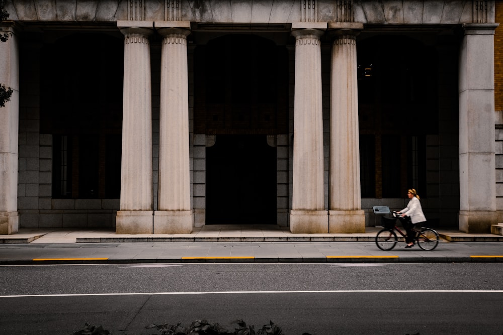 Une femme faisant du vélo dans une rue devant un grand immeuble