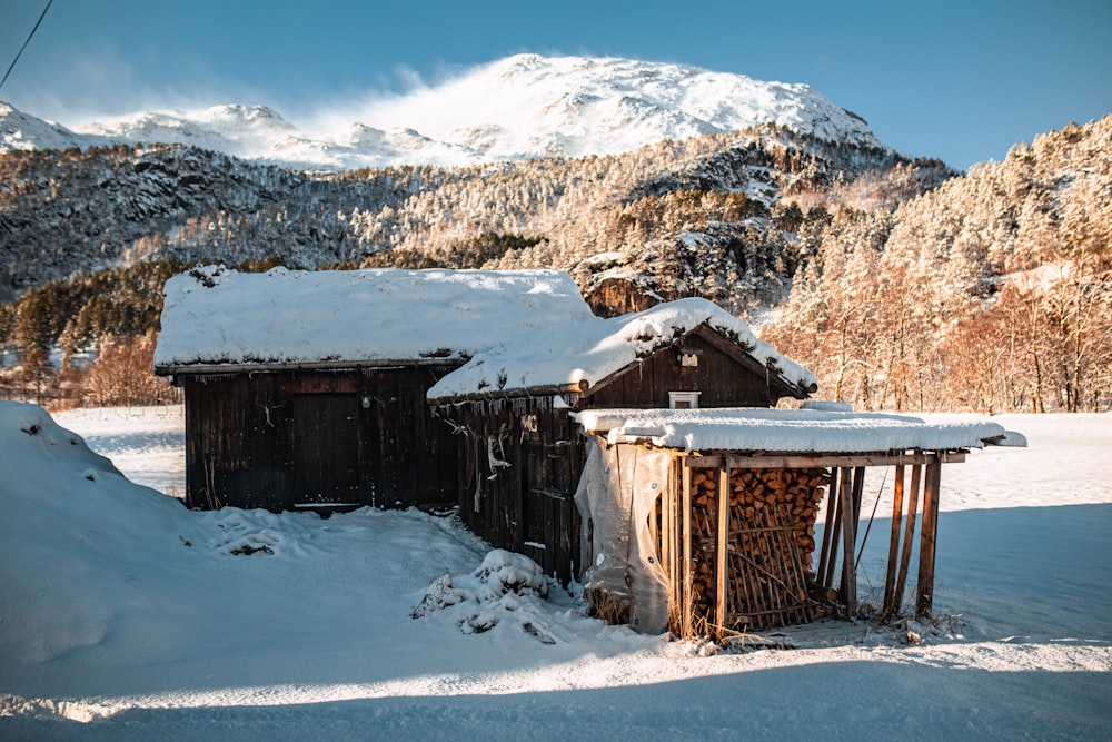 a snowy landscape with a small cabin and mountains in the background