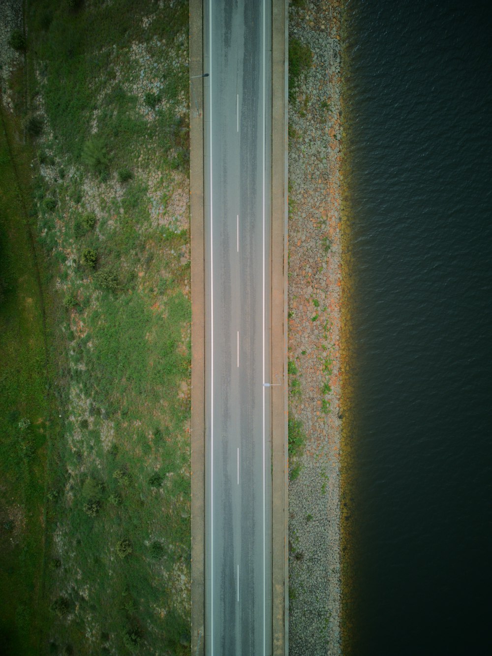 an aerial view of a road near a body of water