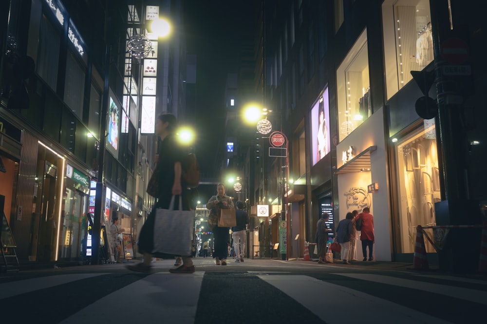 a group of people walking down a street at night