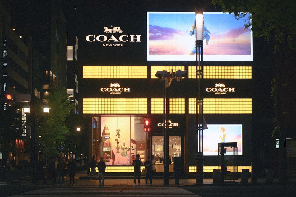 a coach store lit up at night on a city street