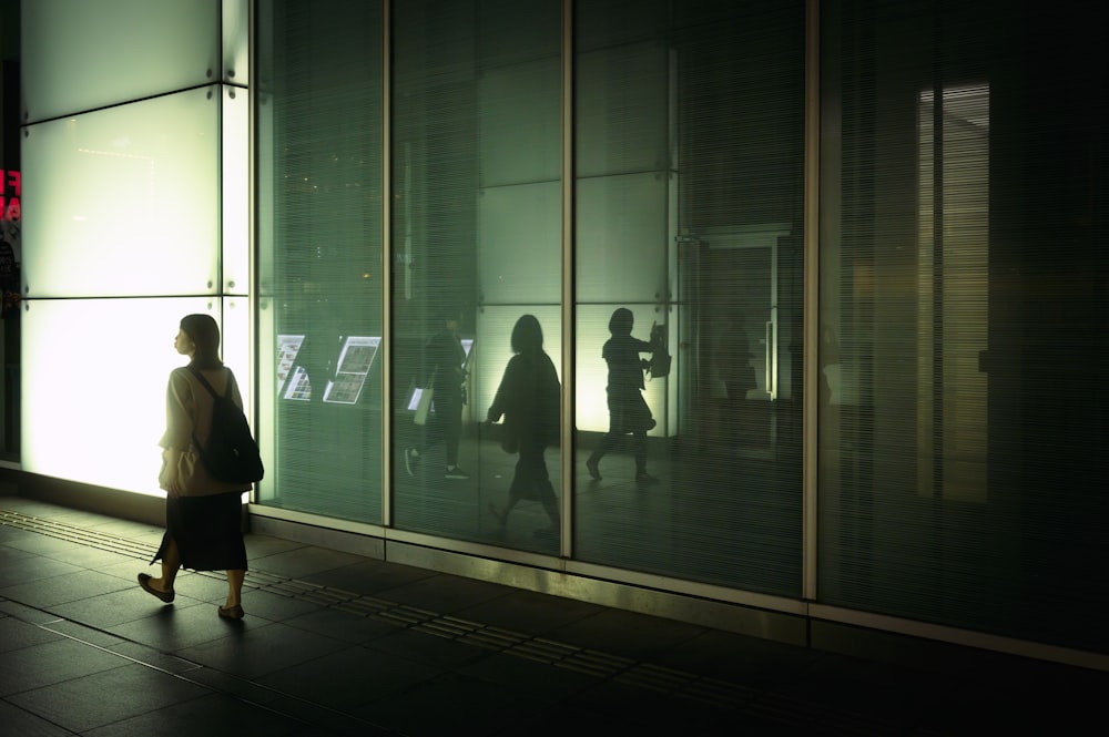 a woman walking down a sidewalk next to a tall building