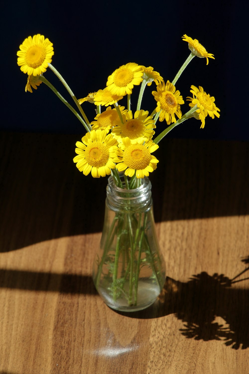 a vase filled with yellow flowers on top of a wooden table