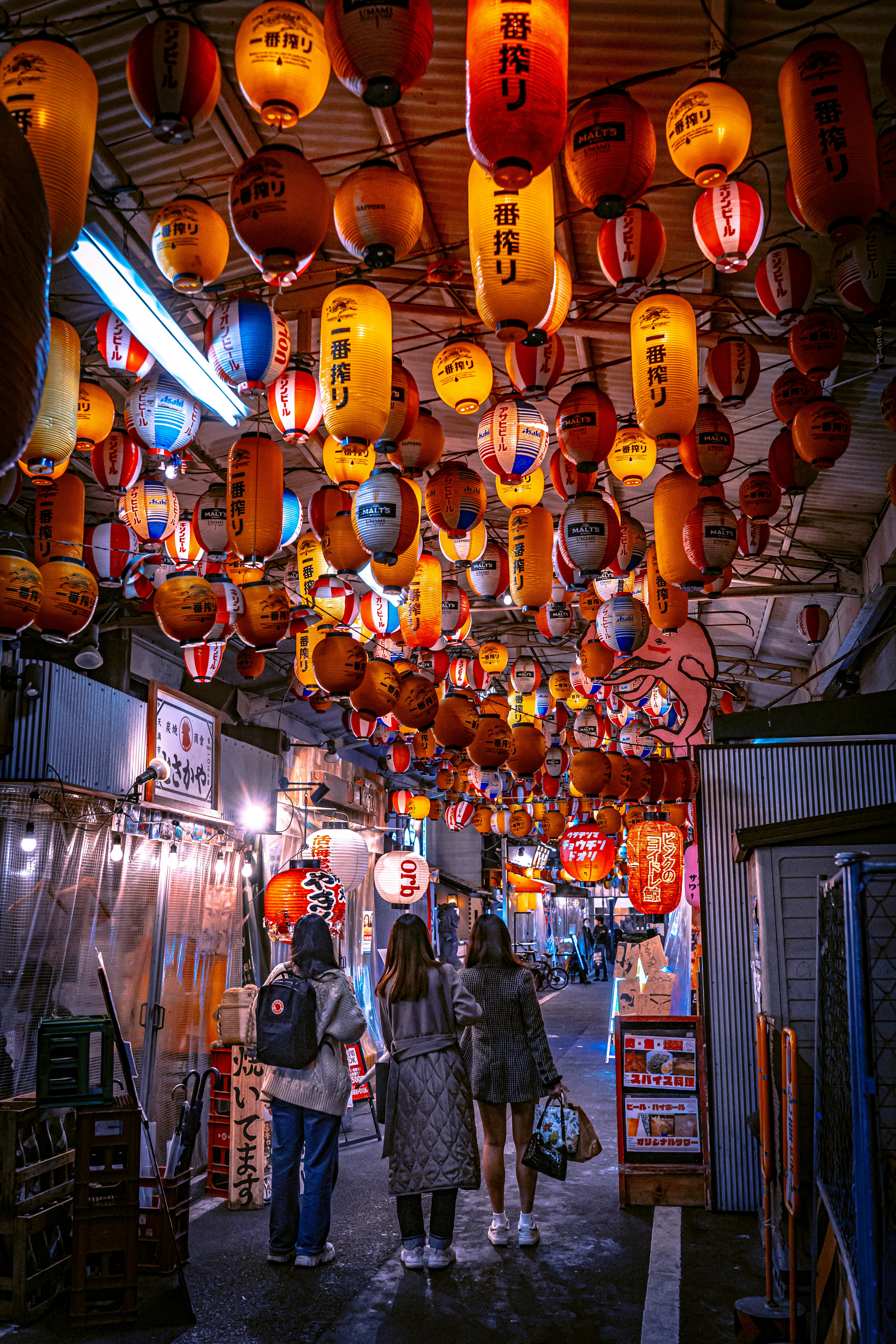 un grupo de personas caminando por una calle bajo linternas