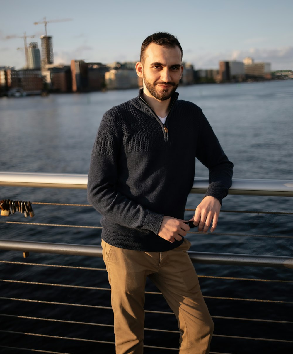 a man standing on a bridge next to a body of water