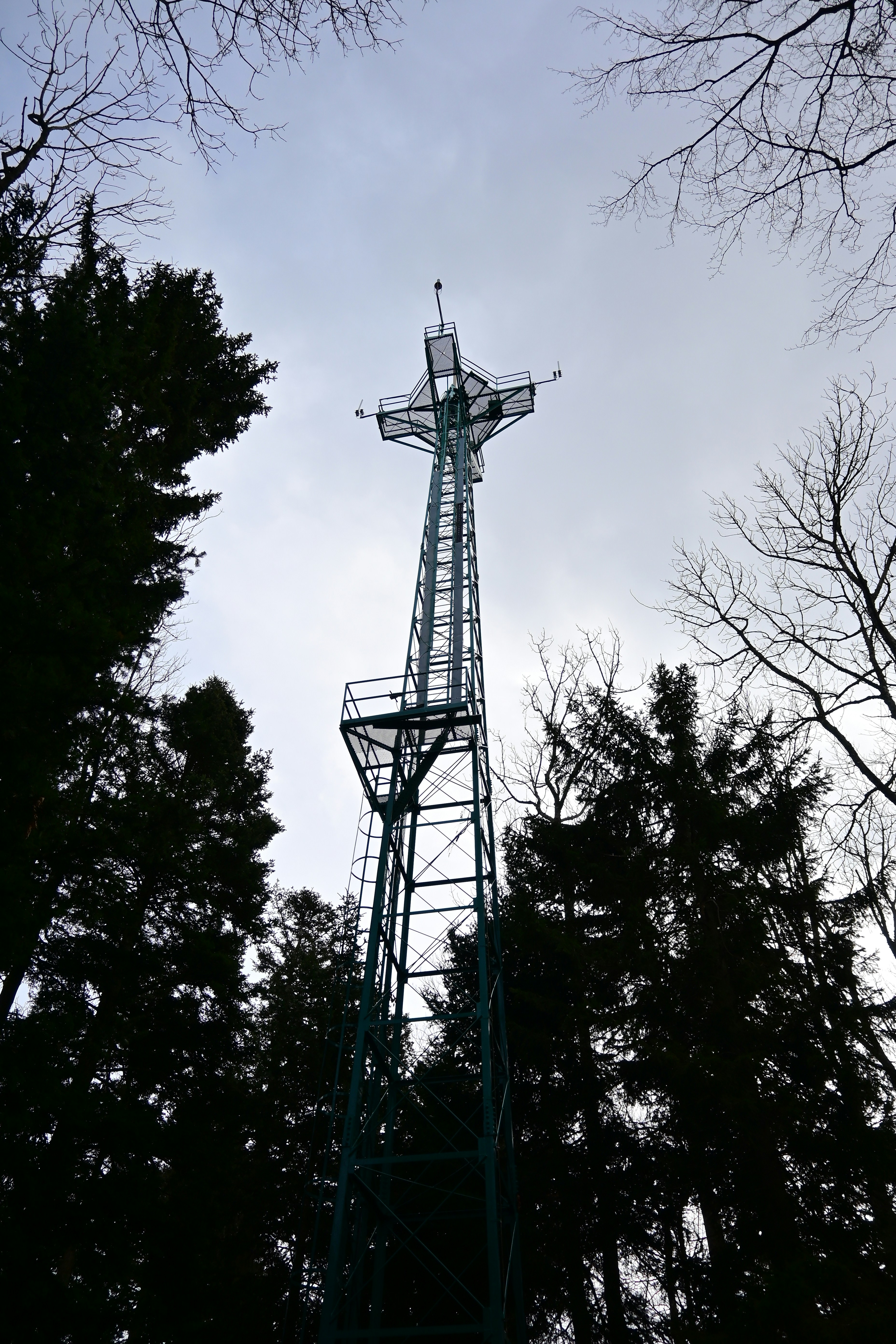a tall metal tower with a cross on top of it