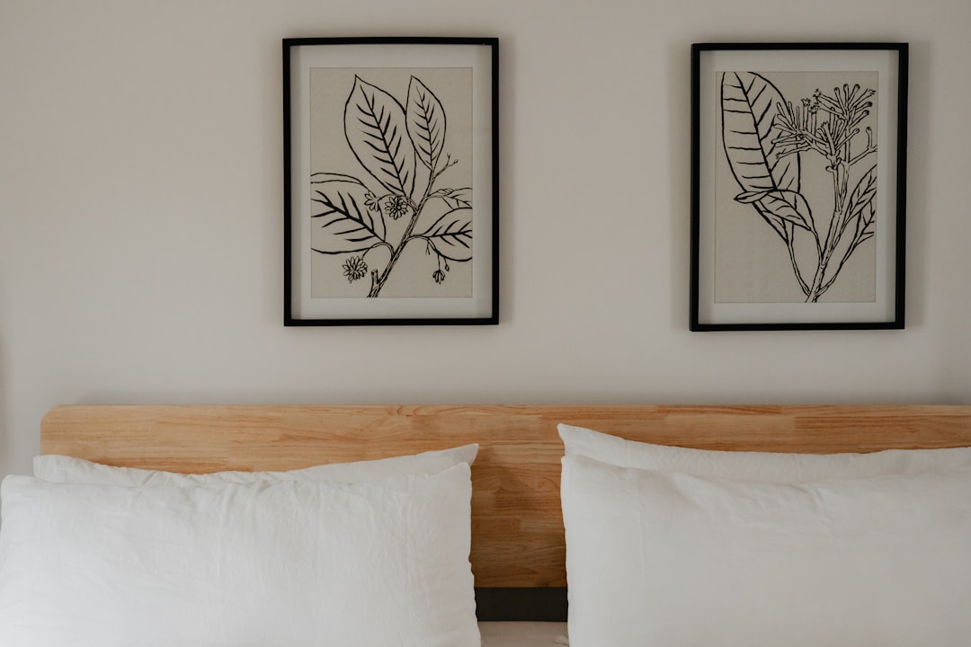 Minimal bedroom headboard with two framed black and white botanical art prints on white wall