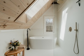 a bathroom with a wooden ceiling and a white bathtub