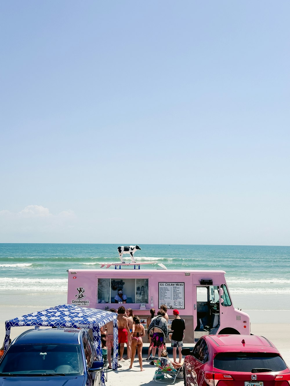a group of people standing around a food truck on the beach
