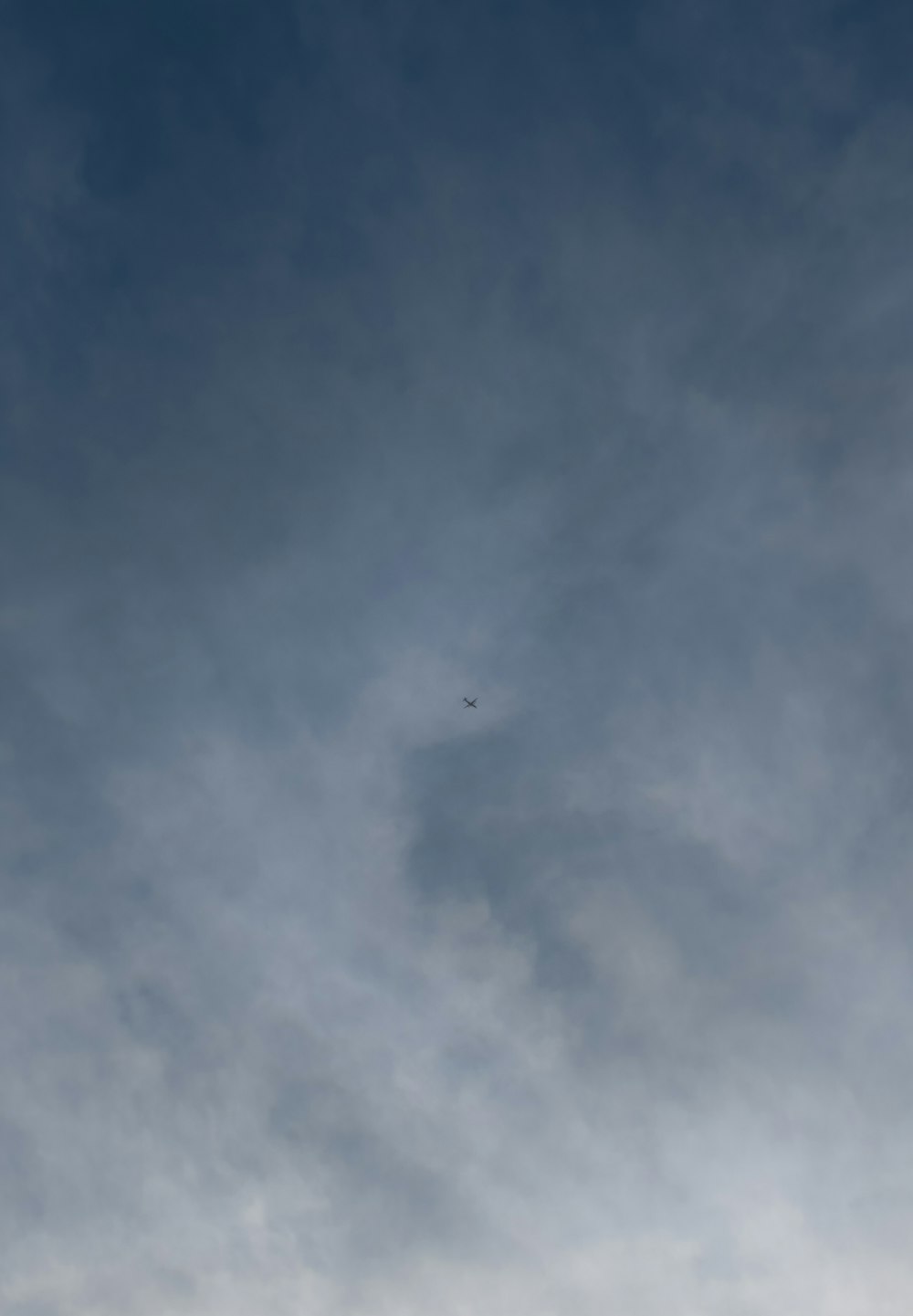 a plane flying through a cloudy blue sky