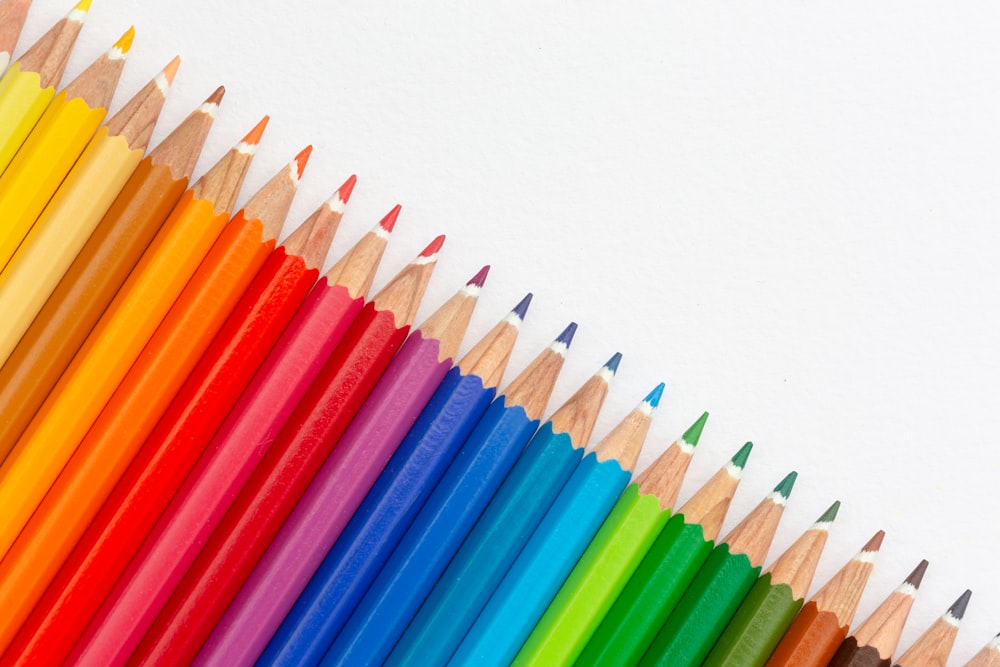 a row of colored pencils with a white background