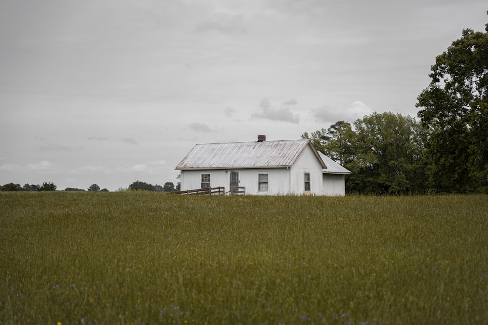 a white house in a field with trees in the background