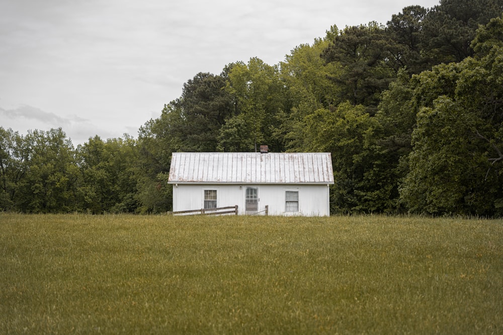 a white house in a field with trees in the background