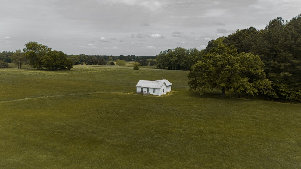 an aerial view of a small white house in the middle of a field