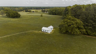 an aerial view of a small white house in the middle of a field