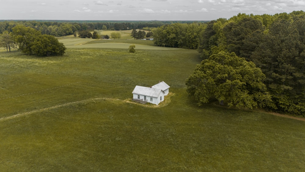 an aerial view of a small white house in the middle of a field