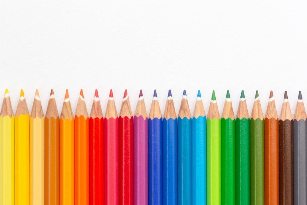 a row of colored pencils lined up against a white background