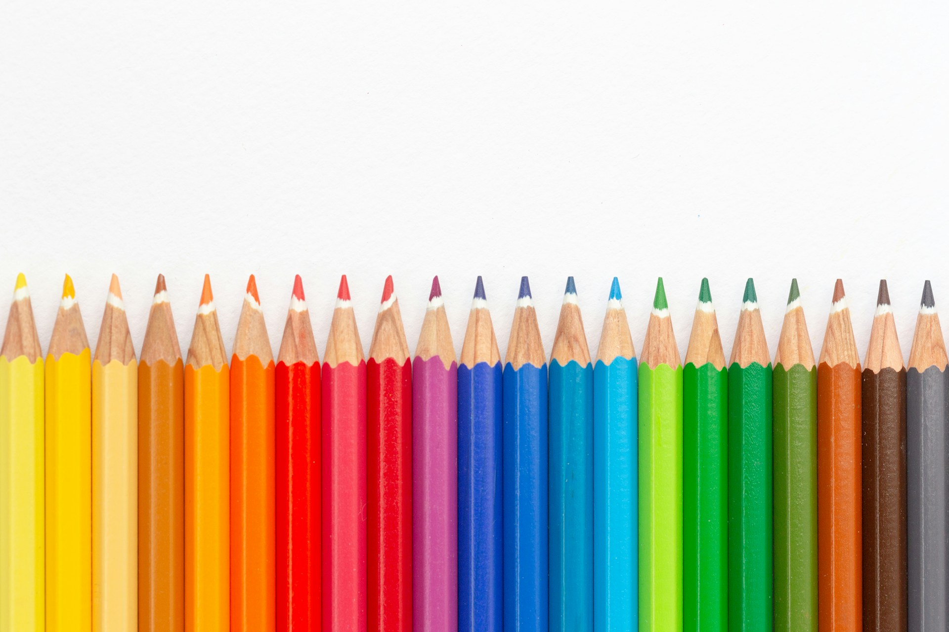a row of colored pencils lined up against a white background