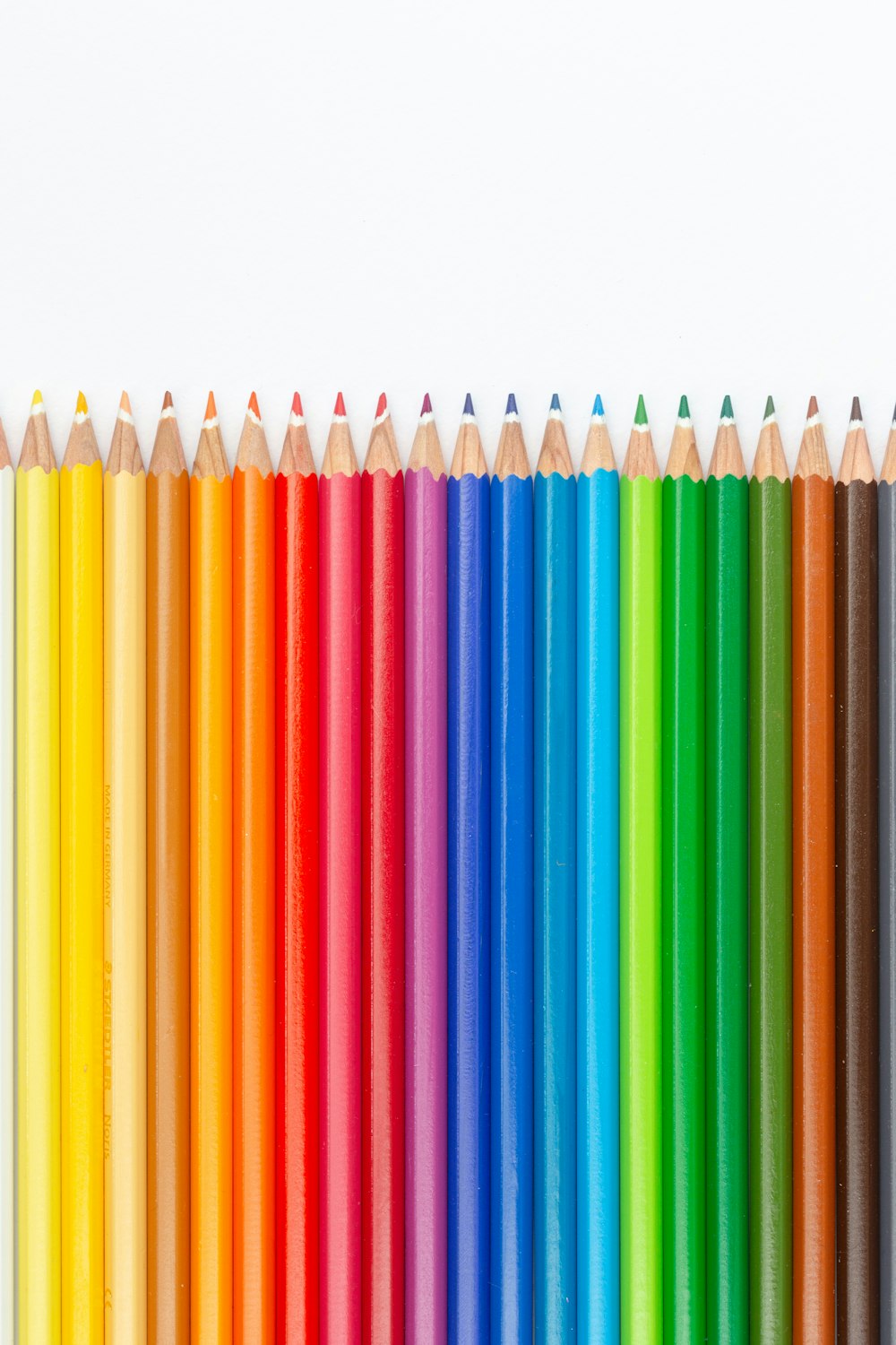 a row of colored pencils lined up against a white background