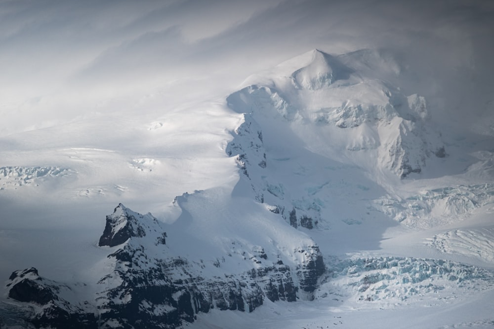 a large mountain covered in snow under a cloudy sky