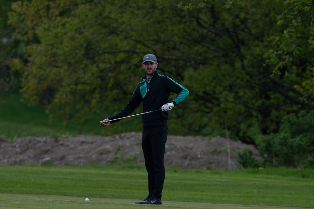 a man standing on top of a green field holding a golf club