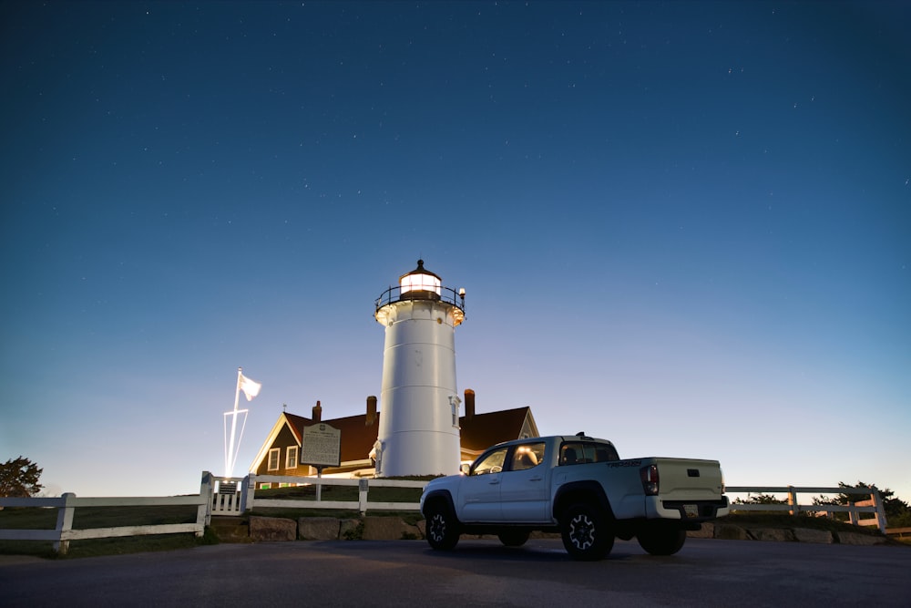 a white truck parked in front of a light house