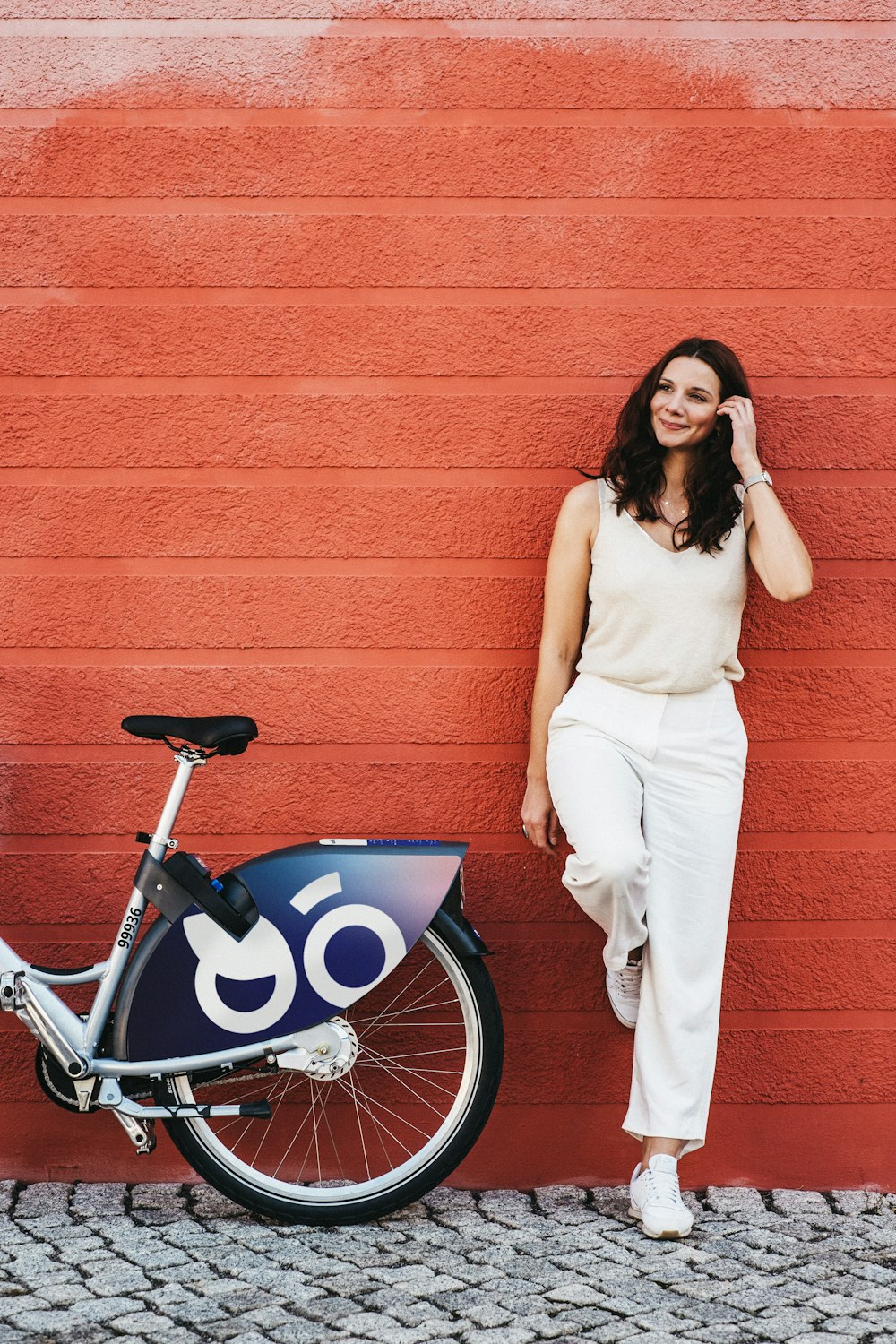 a woman leaning against a wall next to a bike