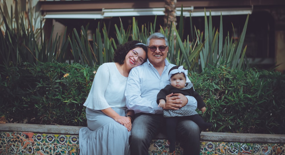 a man and woman sitting on a bench with a baby