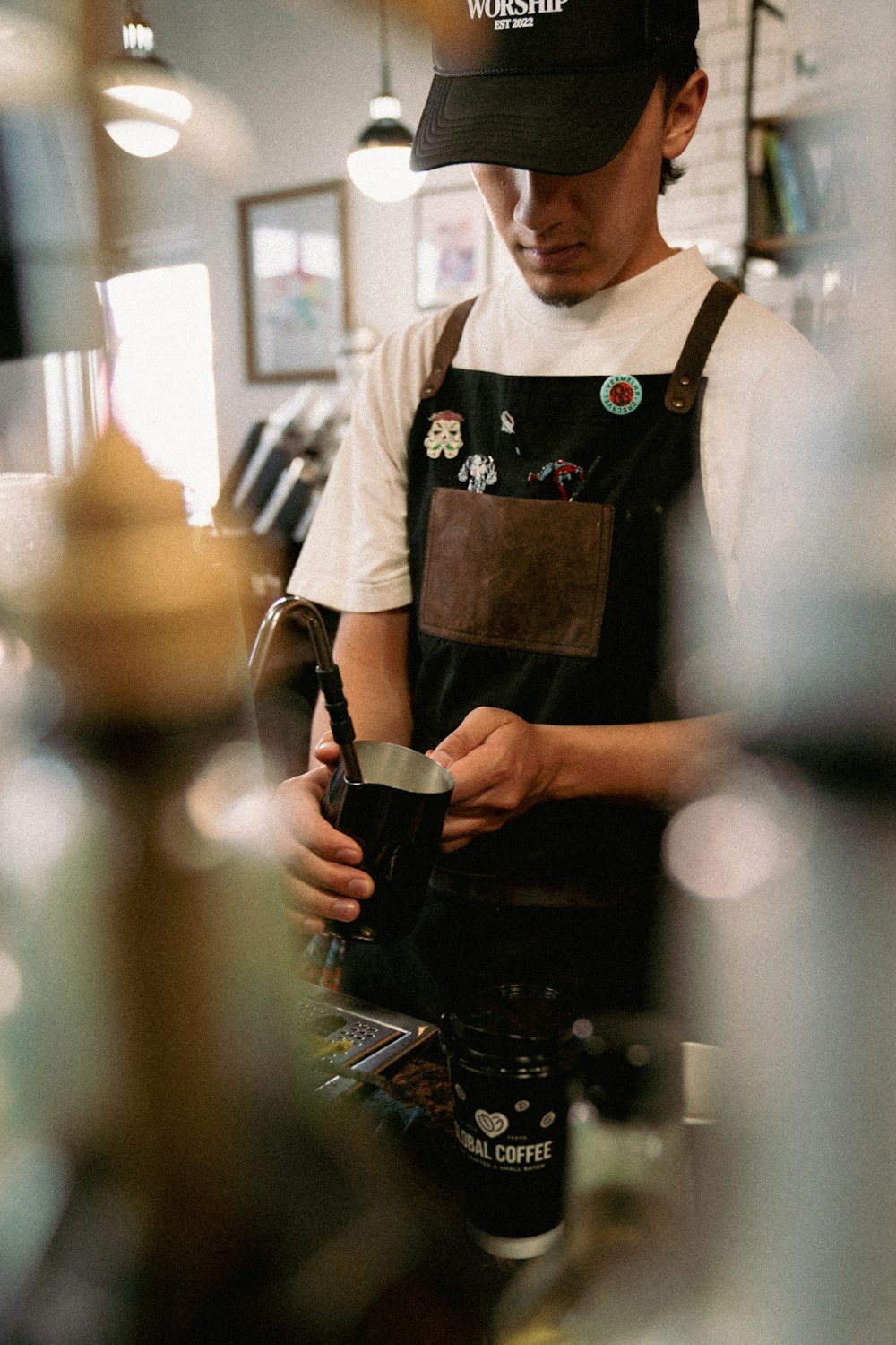 a man in an apron and hat is pouring a cup of coffee