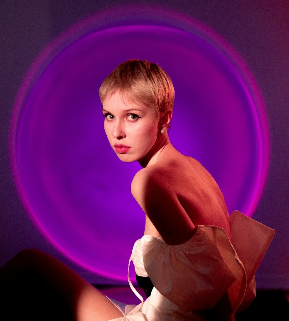 a woman in a white dress sitting in front of a purple circle