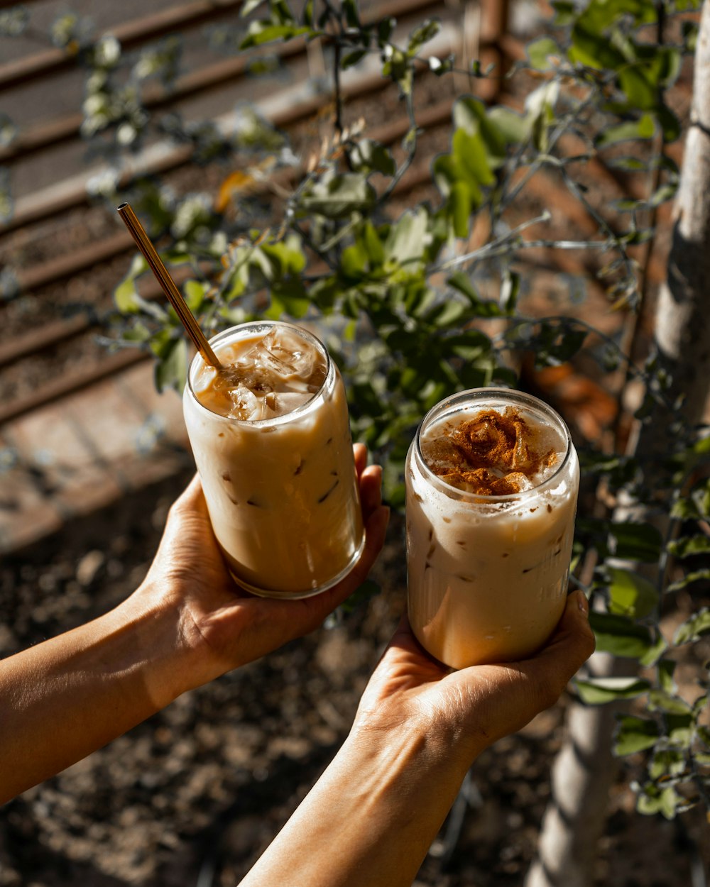 two people holding up glasses with drinks in them