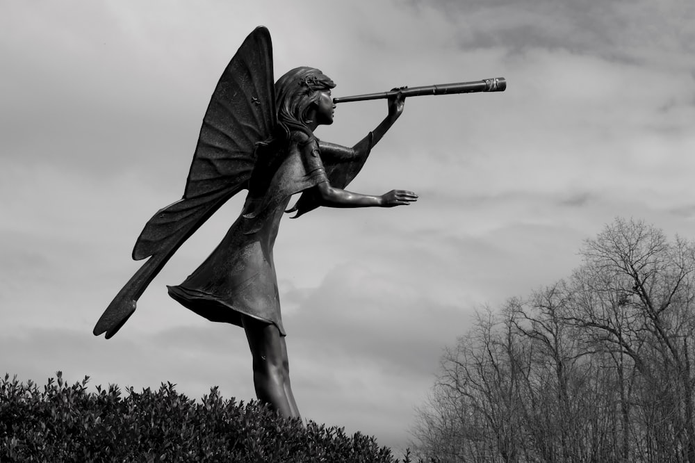 a black and white photo of a statue of a woman holding a telescope