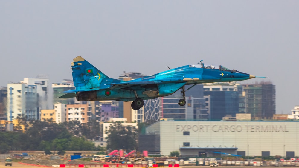 a blue fighter jet taking off from a runway