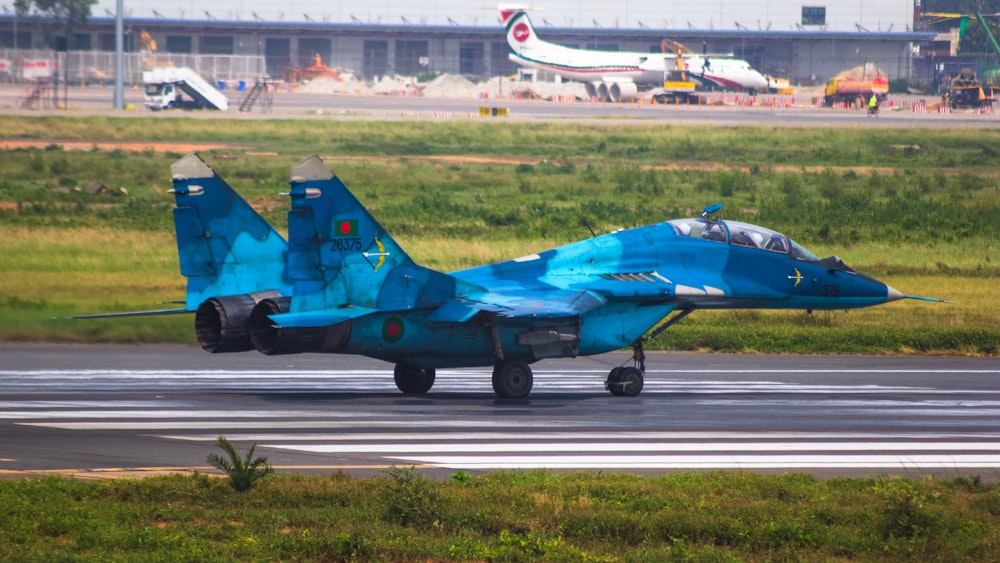 a blue fighter jet sitting on top of an airport runway