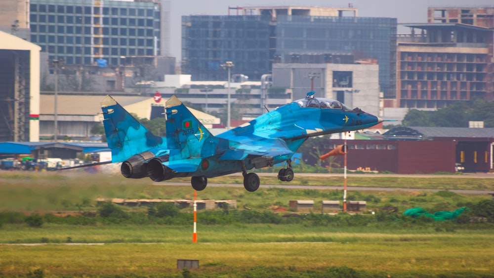 a blue fighter jet taking off from an airport runway