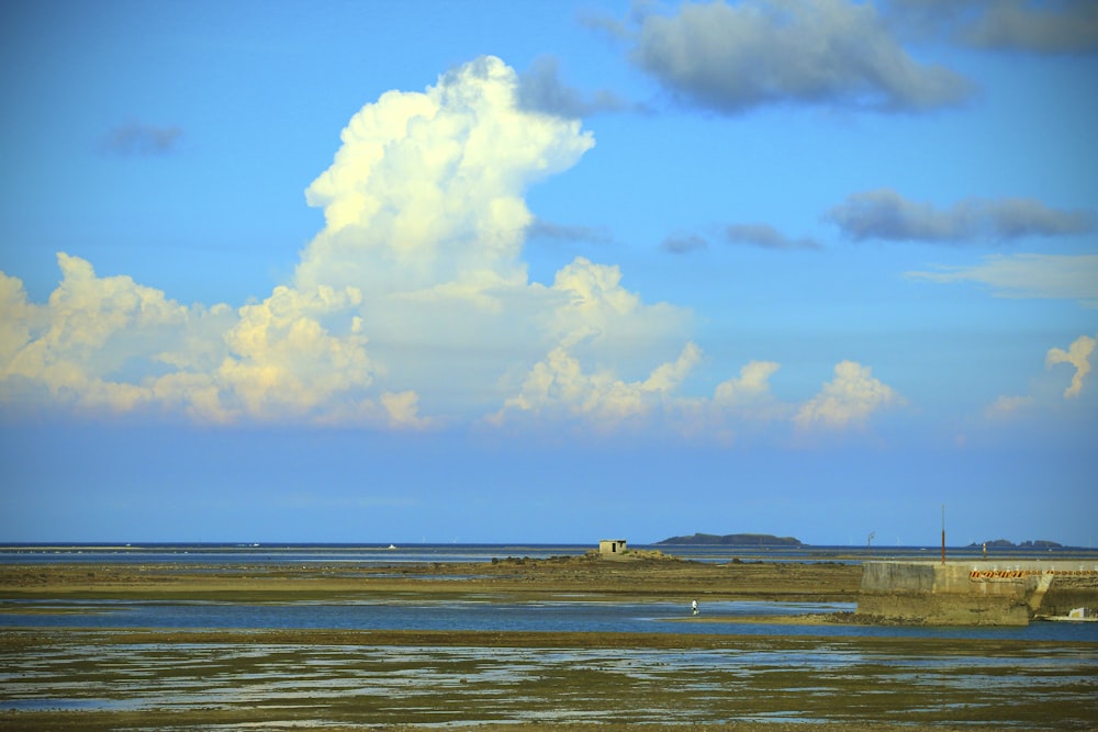 a large body of water sitting under a cloudy blue sky