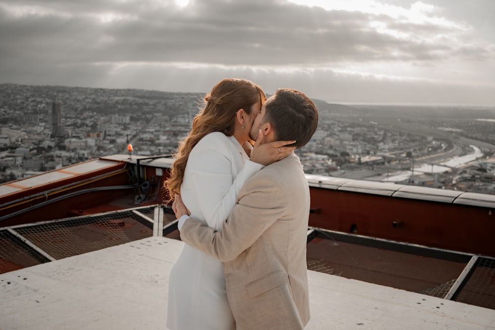 a man and woman kissing on top of a building