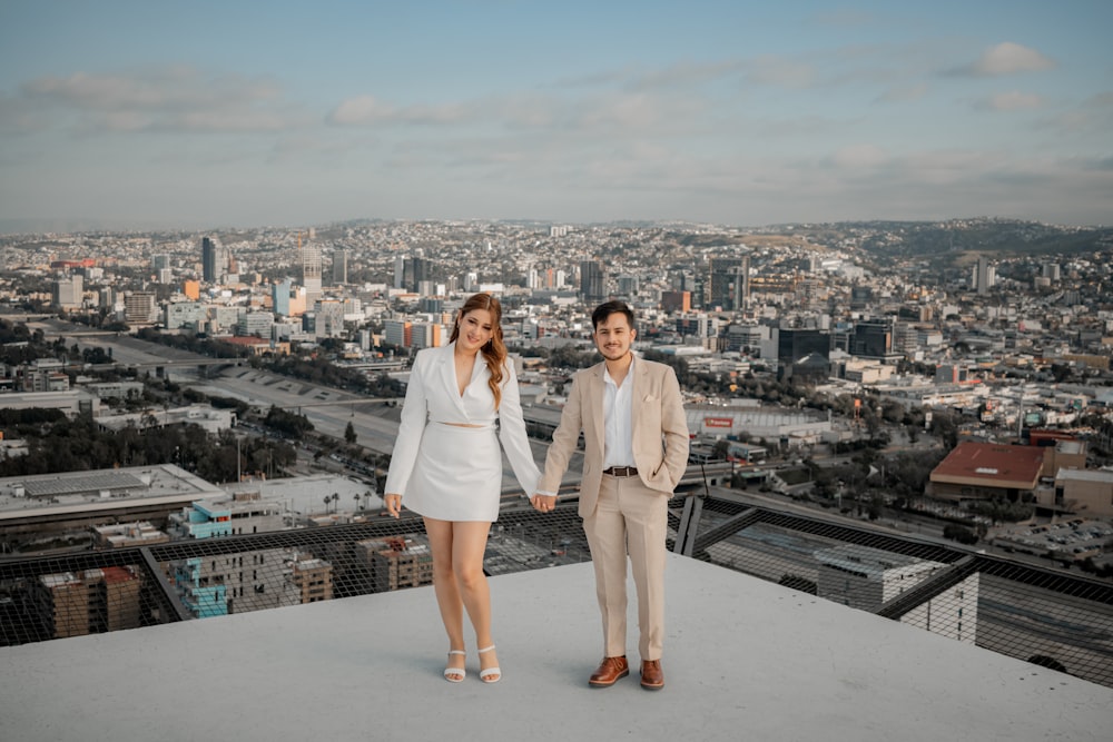 a man and a woman holding hands on top of a building