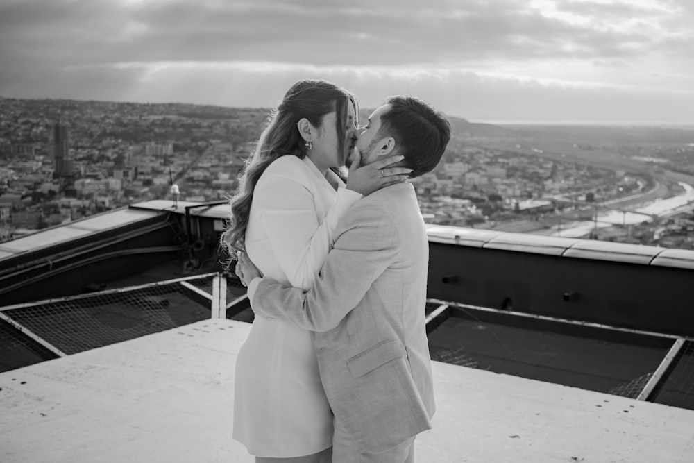 a man and woman kissing on top of a building