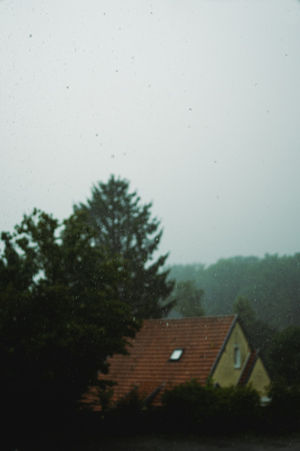 a yellow house with a red roof in the rain