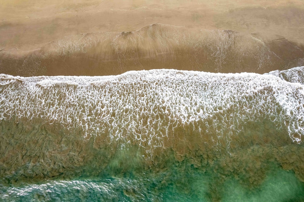 an aerial view of a beach with waves and sand