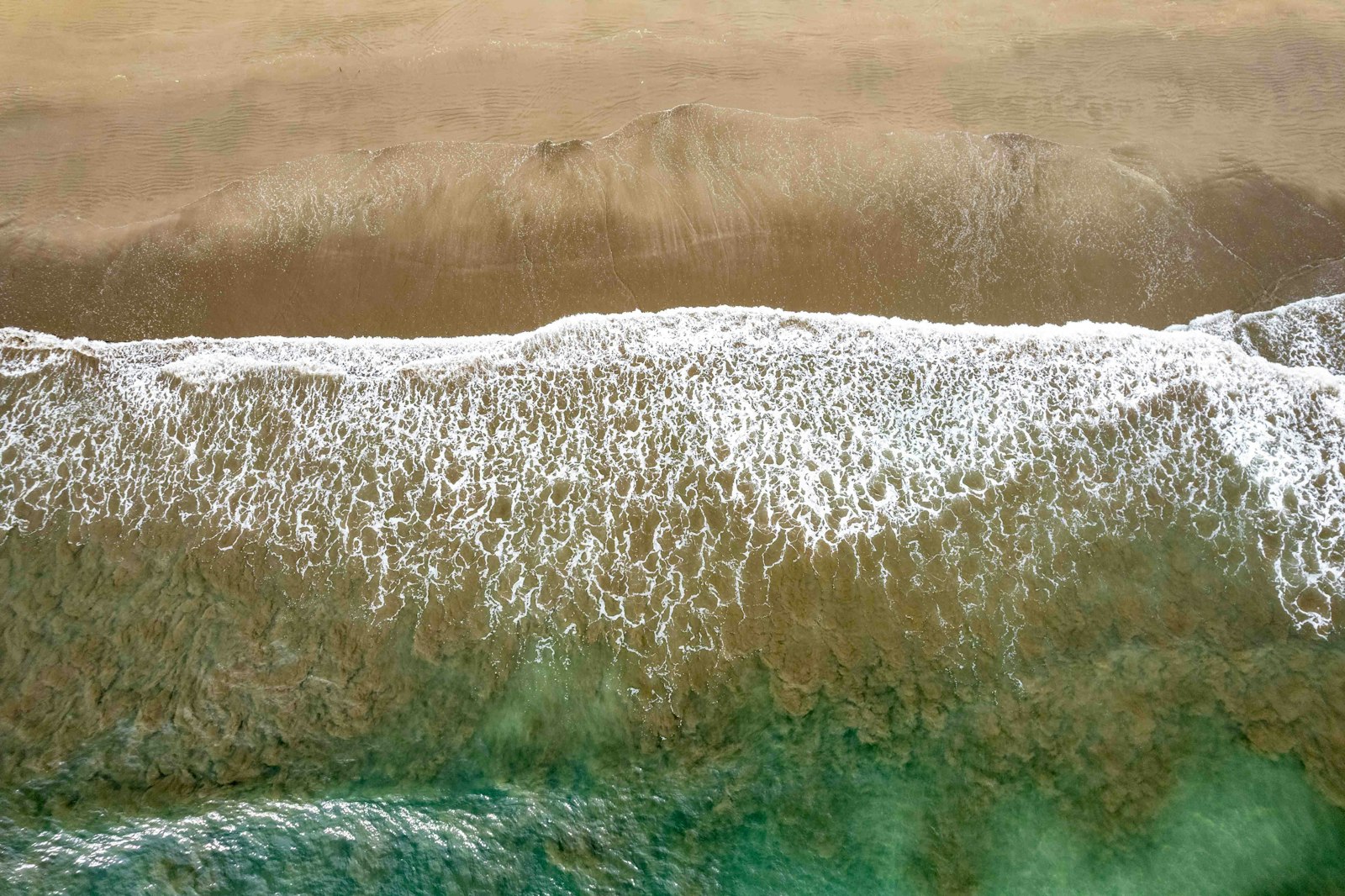Aerial view of a turquoise sea meeting a sandy tropical shoreline, evoking the summery settings of Emily Henry's romance novels