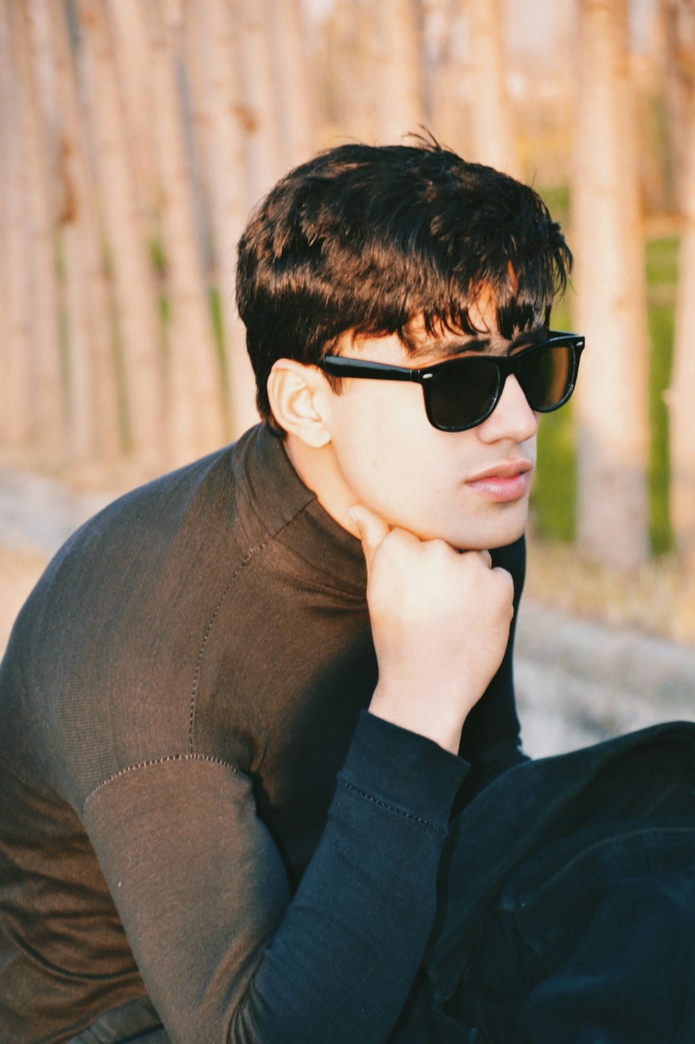 a young man wearing sunglasses sitting on a bench